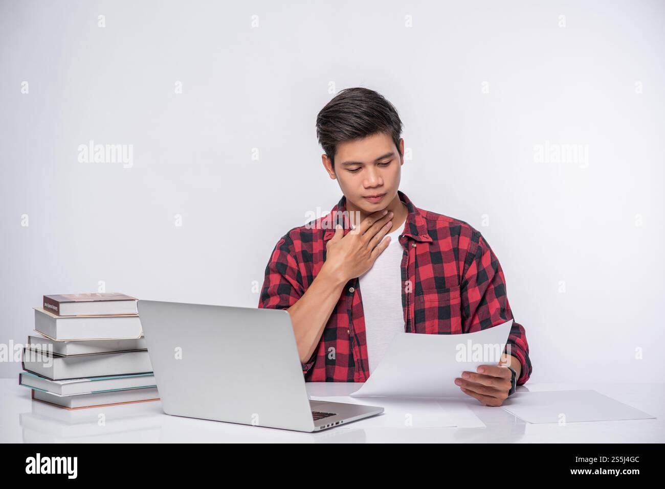 Un uomo che usa un portatile in ufficio e fa un'analisi documentale. Foto Stock