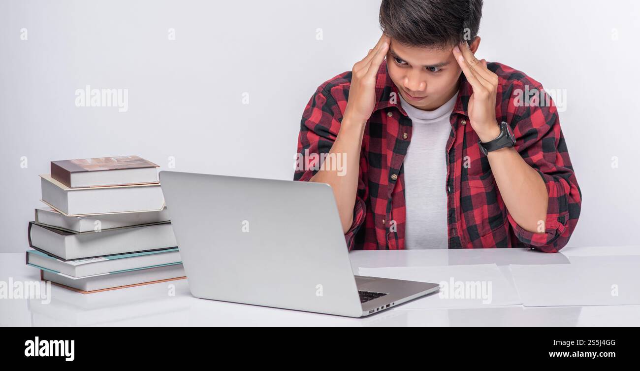 Gli uomini utilizzano i computer portatili in ufficio e sono stressati. Foto Stock