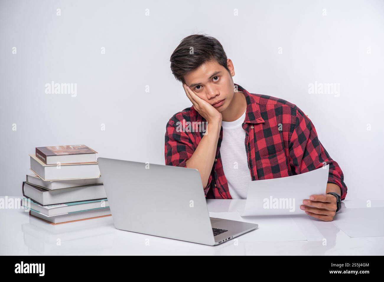 Un uomo che usa un portatile in ufficio e fa un'analisi documentale. Foto Stock