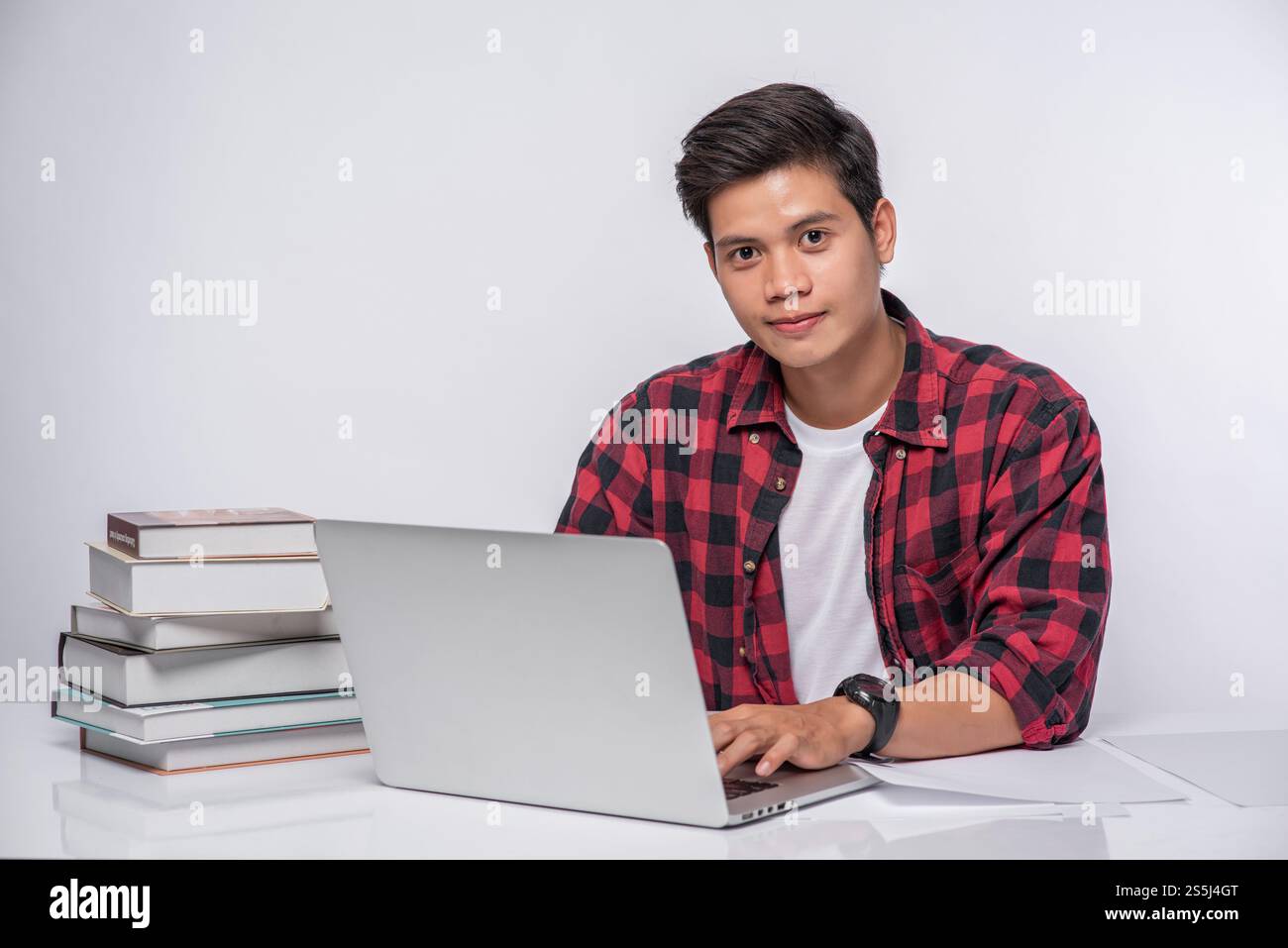 Un uomo che indossa una camicia a righe usa un notebook per lavorare. Foto Stock