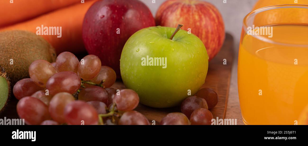 Mele verdi, uva e succo d'arancia poggiati a terra. Foto Stock