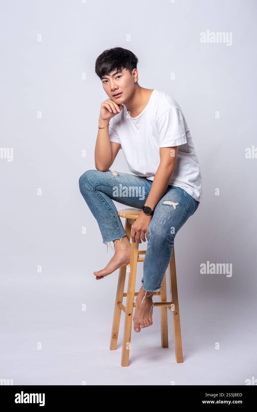 Un giovane uomo in una T-shirt bianca è seduto su un seggiolone. Foto Stock