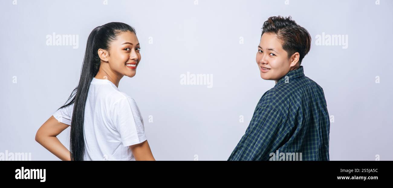 Una donna di due amanti si è messa mano nella mano, si è guardata indietro e si è girata. Foto Stock