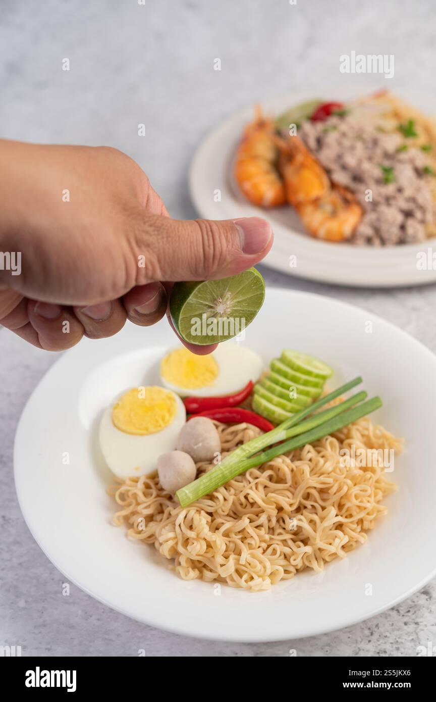 Mamma con uova sode in un piatto bianco, insieme a limoni, peperoncini e polpette. Foto Stock