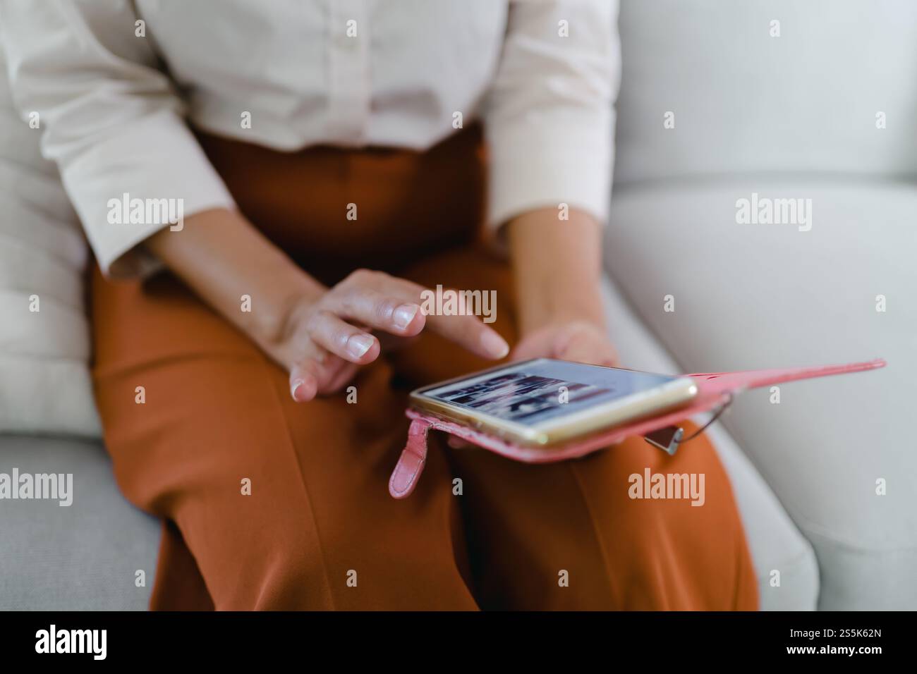 Donna asiatica di mezza età che tiene il telefono cellulare. donna anziana con smartphone. donna anziana che utilizza lo smartphone a casa con il concetto di tecnologia. Foto Stock