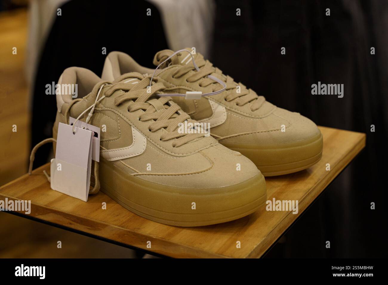 Minsk, Bielorussia - 16 agosto 2024: Le nuove sneakers beige vengono presentate elegantemente su uno stand in legno all'interno di una boutique alla moda, mettendo in risalto il loro stato di salute Foto Stock