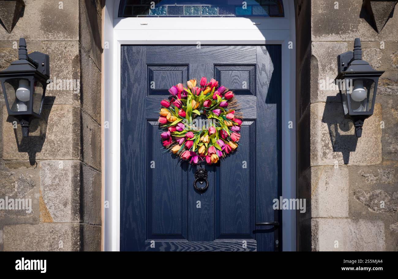 Corona di tulipani floreali appesa alla porta anteriore dipinta di nero di una casa storica, Regno Unito Foto Stock