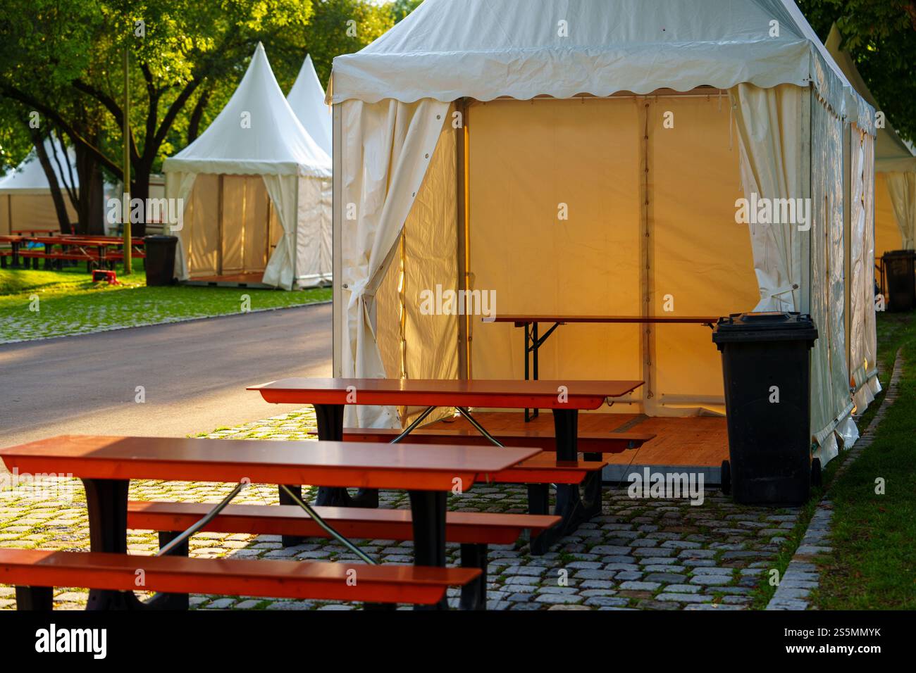 Tenda bianca con panche rosse e tavoli all'aperto in una giornata di sole. Foto Stock