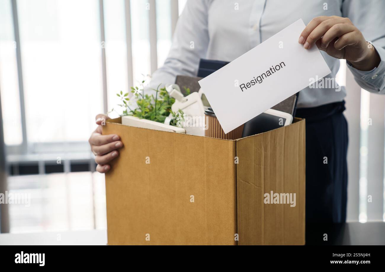 Donna d'affari che invia una lettera di dimissioni e materiale da imballaggio, si dimette dalla depressione o porta con sé una scatola di cartone da lavoro alla scrivania in ufficio. Cambio di lavoro o. Foto Stock Donna d'affari che invia una lettera di dimissioni e materiale da imballaggio, si dimette dalla depressione o porta con sé una scatola di cartone da lavoro alla scrivania in ufficio. Cambio di lavoro o. Foto Stock