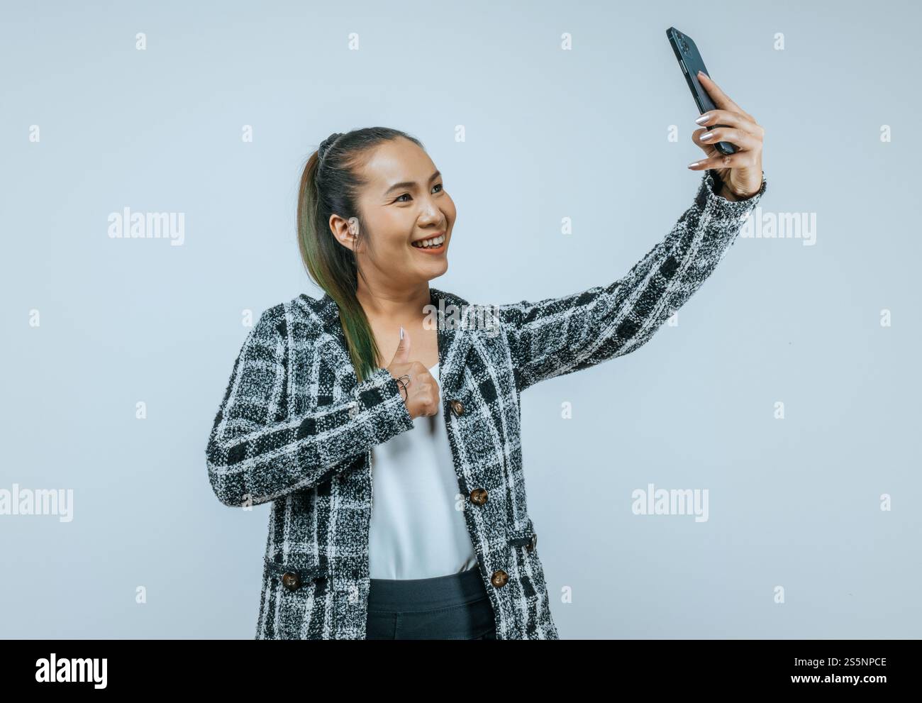 Ritratto di una donna d'affari asiatica felice che usa il telefono cellulare isolato sullo sfondo con spazio di copia. Donna che tiene e guarda lo smartphone mentre Foto Stock