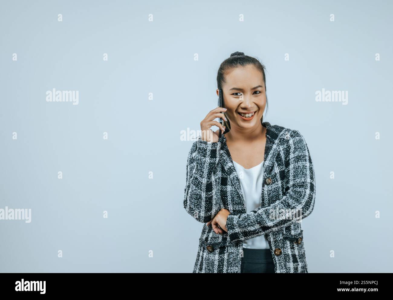 Ritratto di una donna d'affari asiatica felice che usa il telefono cellulare isolato sullo sfondo con spazio di copia. Donna che tiene e guarda lo smartphone mentre Foto Stock