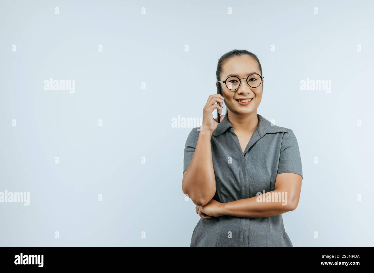 Ritratto di una donna d'affari asiatica felice che usa il telefono cellulare isolato sullo sfondo con spazio di copia. Donna che tiene e guarda la fotocamera mentre Foto Stock