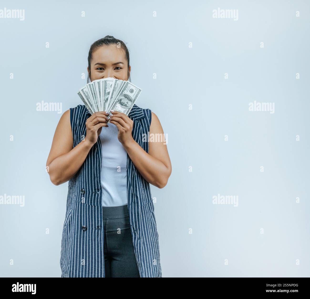 Ritratto di una donna asiatica di successo che tiene in mano i soldi e guarda la macchina fotografica, in piedi sullo sfondo in studio con spazio di copia. Financal e Make Foto Stock