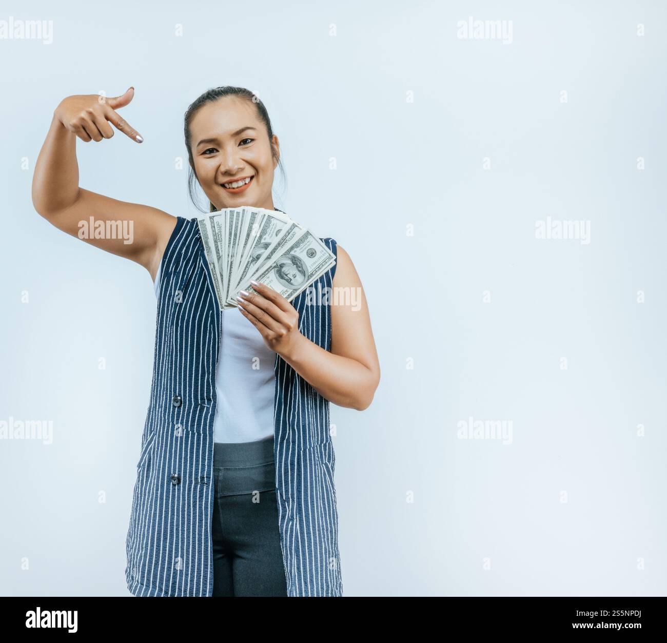 Ritratto di una donna asiatica di successo che tiene in mano i soldi e guarda la macchina fotografica, in piedi sullo sfondo in studio con spazio di copia. Financal e Make Foto Stock