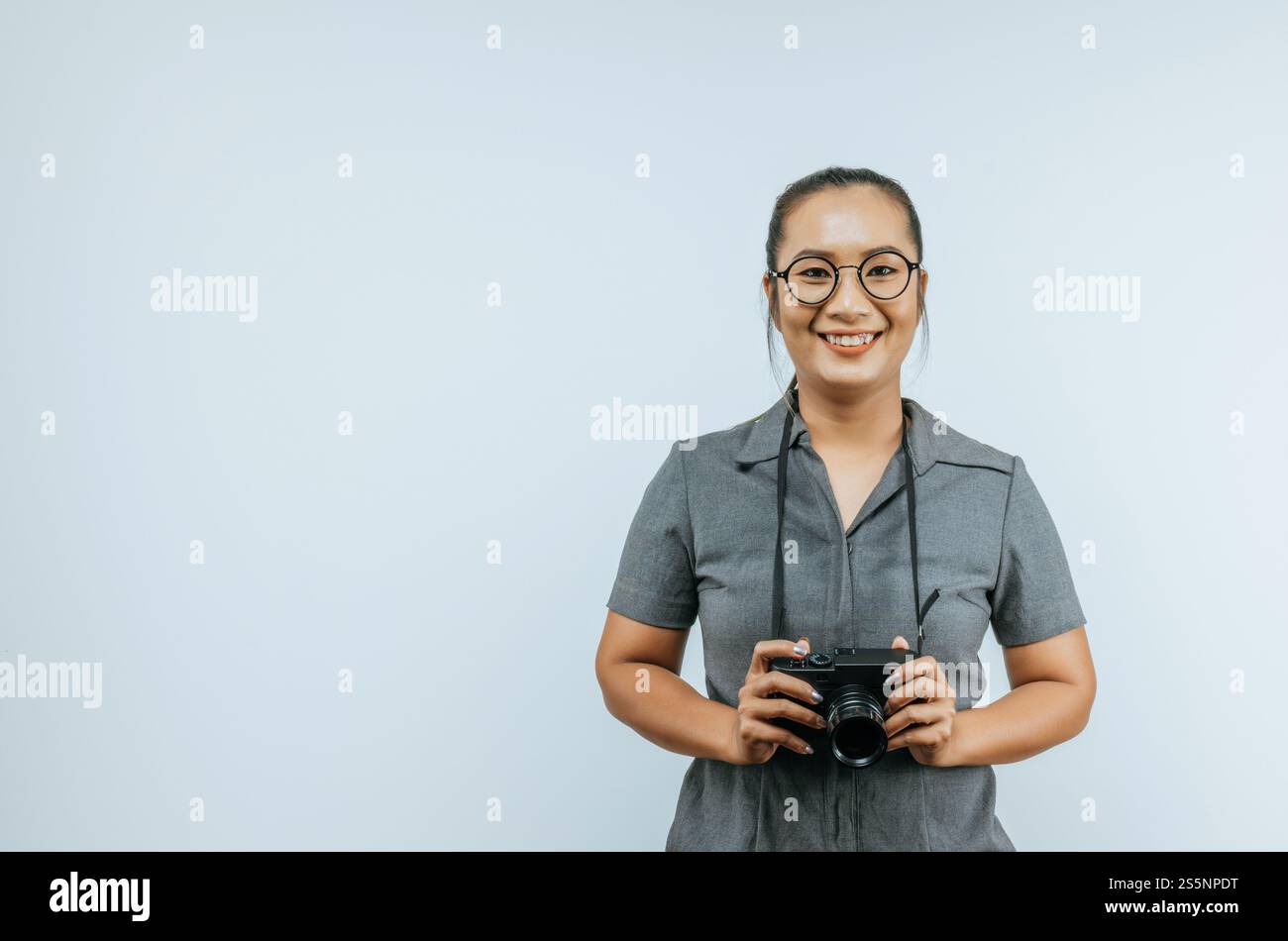Ritratto di occhiali da donna asiatica che indossano abiti casual con un grande sorriso sul viso, tenendo in mano una macchina fotografica che scatta una foto. Background isolato in studio Foto Stock