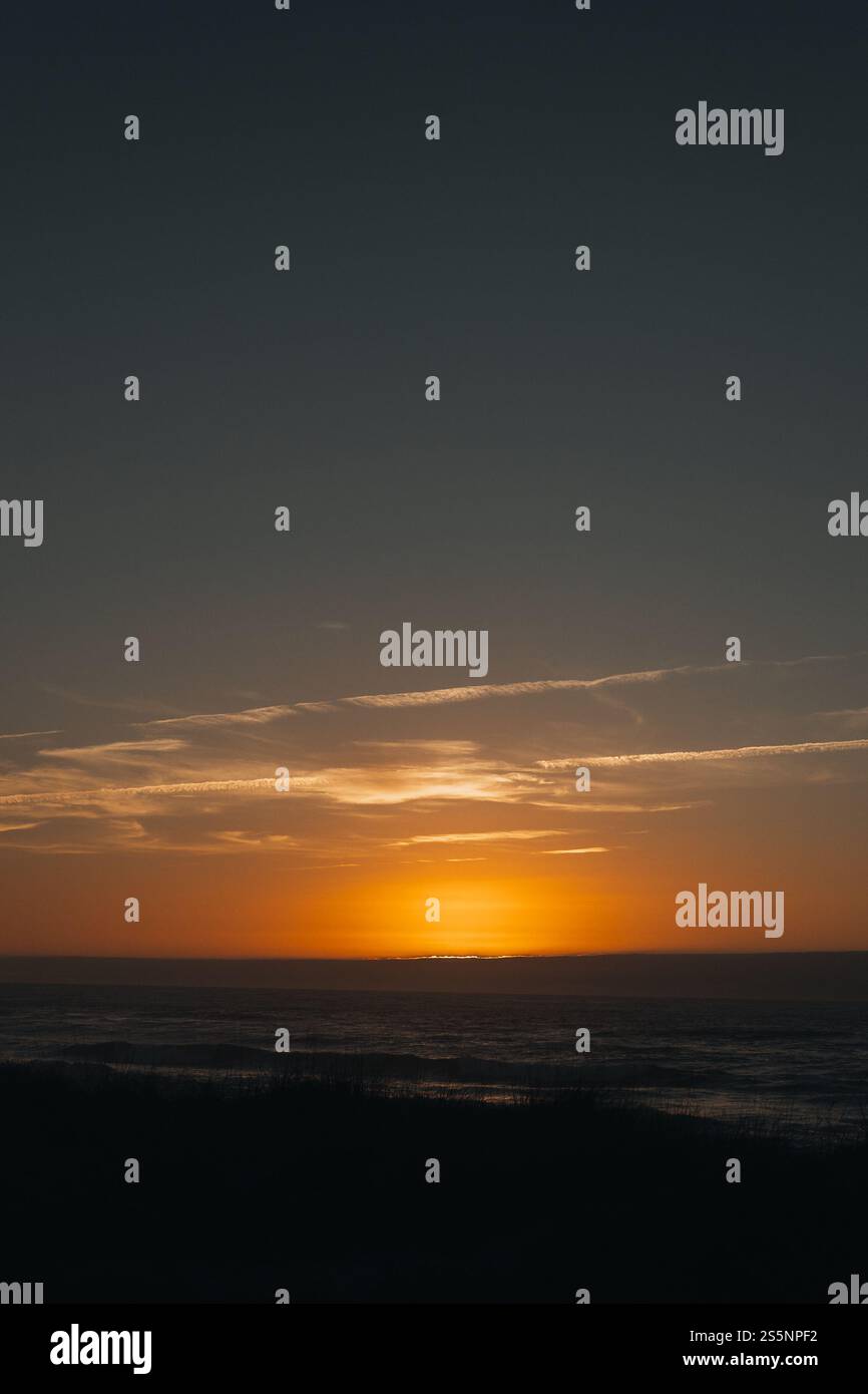 Un vivace tramonto sull'oceano con toni caldi e un orizzonte pulito. Perfetto per viaggi, benessere, design ispiratori o intestazioni di siti Web con spazio per il testo Foto Stock