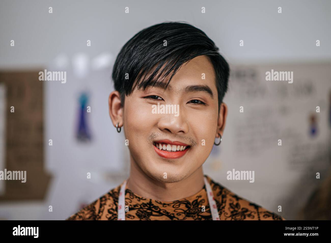 Primo piano di un giovane sarto asiatico felice con un metro a nastro sul collo e guardando la macchina fotografica nello studio di moda. Design e concetto LGBTQ. Foto Stock Primo piano di un giovane sarto asiatico felice con un metro a nastro sul collo e guardando la macchina fotografica nello studio di moda. Design e concetto LGBTQ. Foto Stock