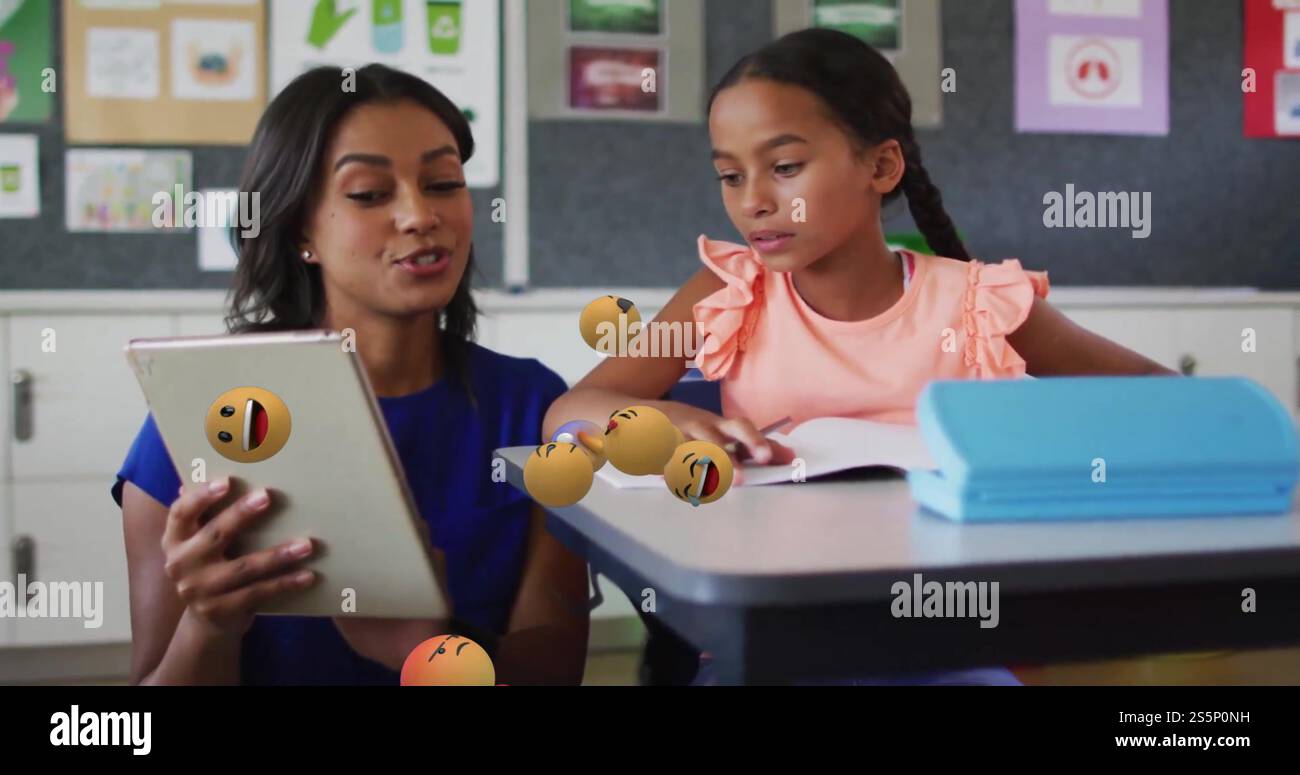 Immagine di icone emoji su studentessa birazziale e insegnante che usa il tablet Foto Stock