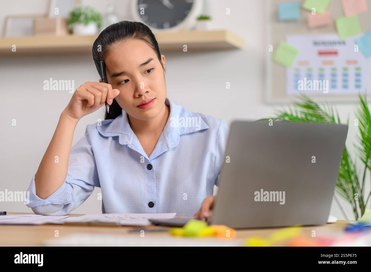 Una lavoratrice donna utilizza un notebook e pensa di risolvere i problemi in ufficio. Foto Stock