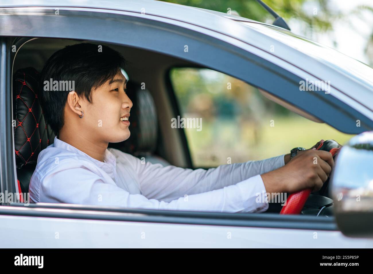Un uomo che guida un'auto apre il finestrino e sorride. Foto Stock