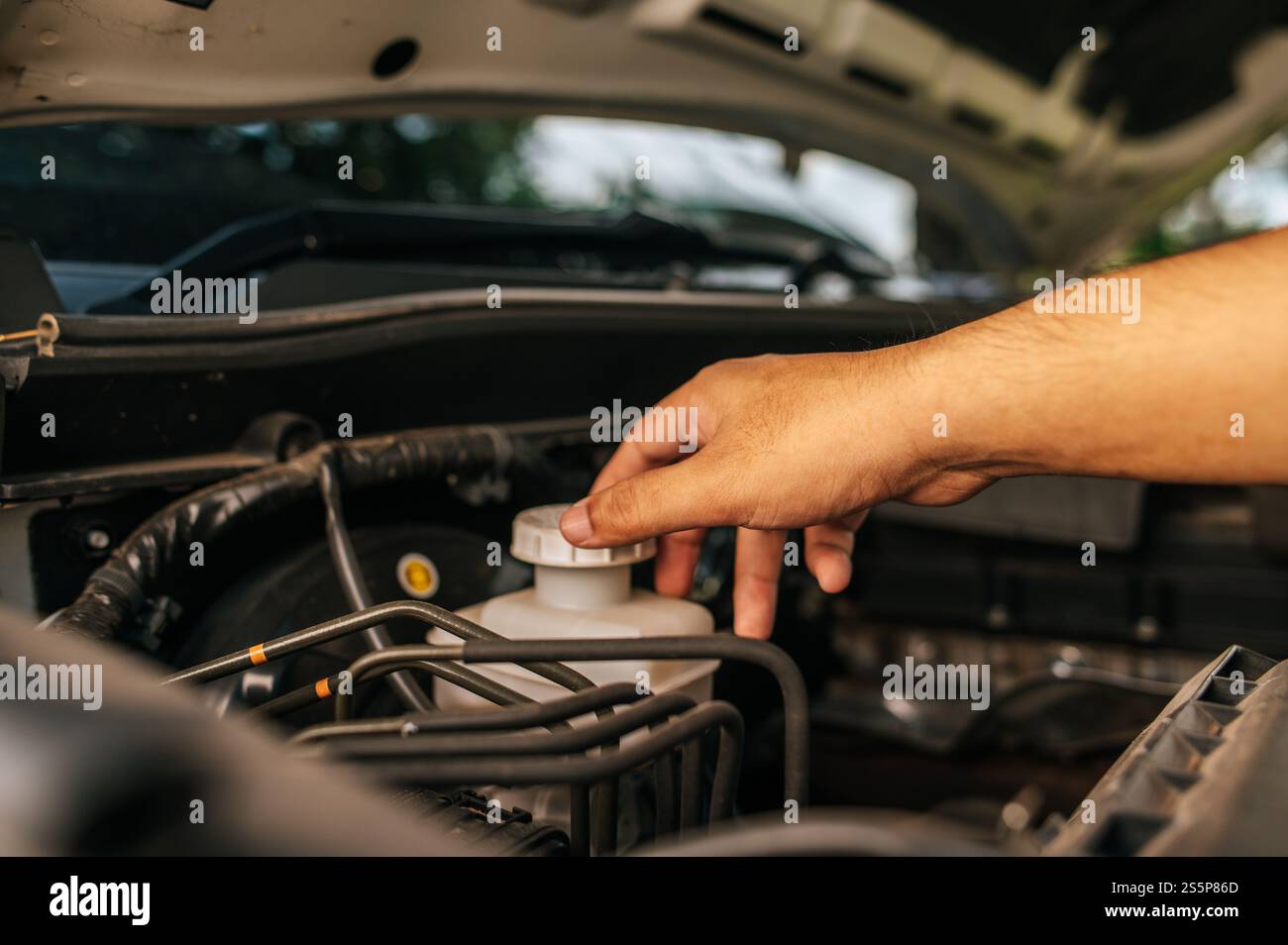 Un uomo apre il cofano di un'auto per riparare l'auto a causa di un guasto. Foto Stock