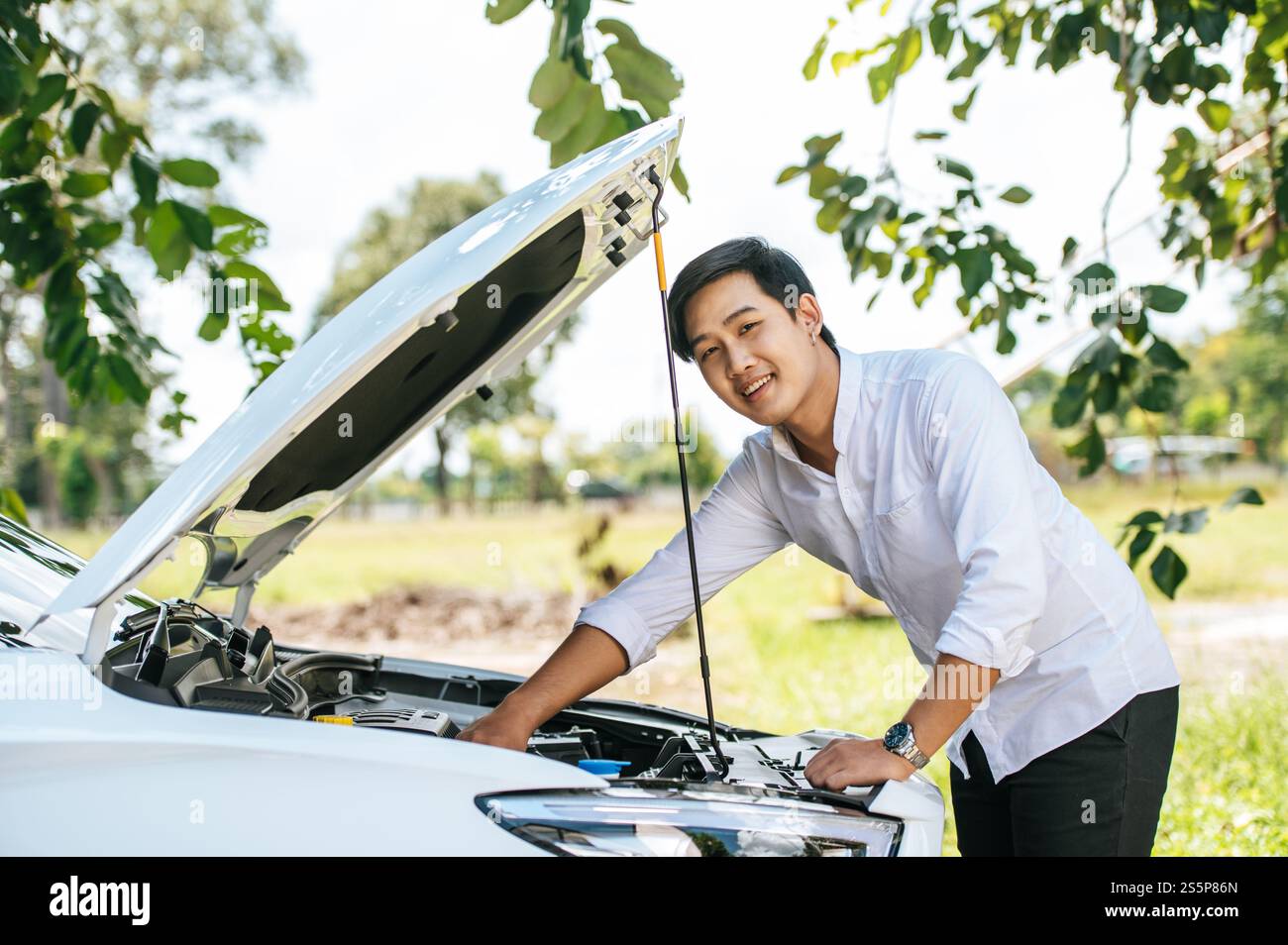 Un uomo apre il cofano di un'auto per riparare l'auto a causa di un guasto. Foto Stock