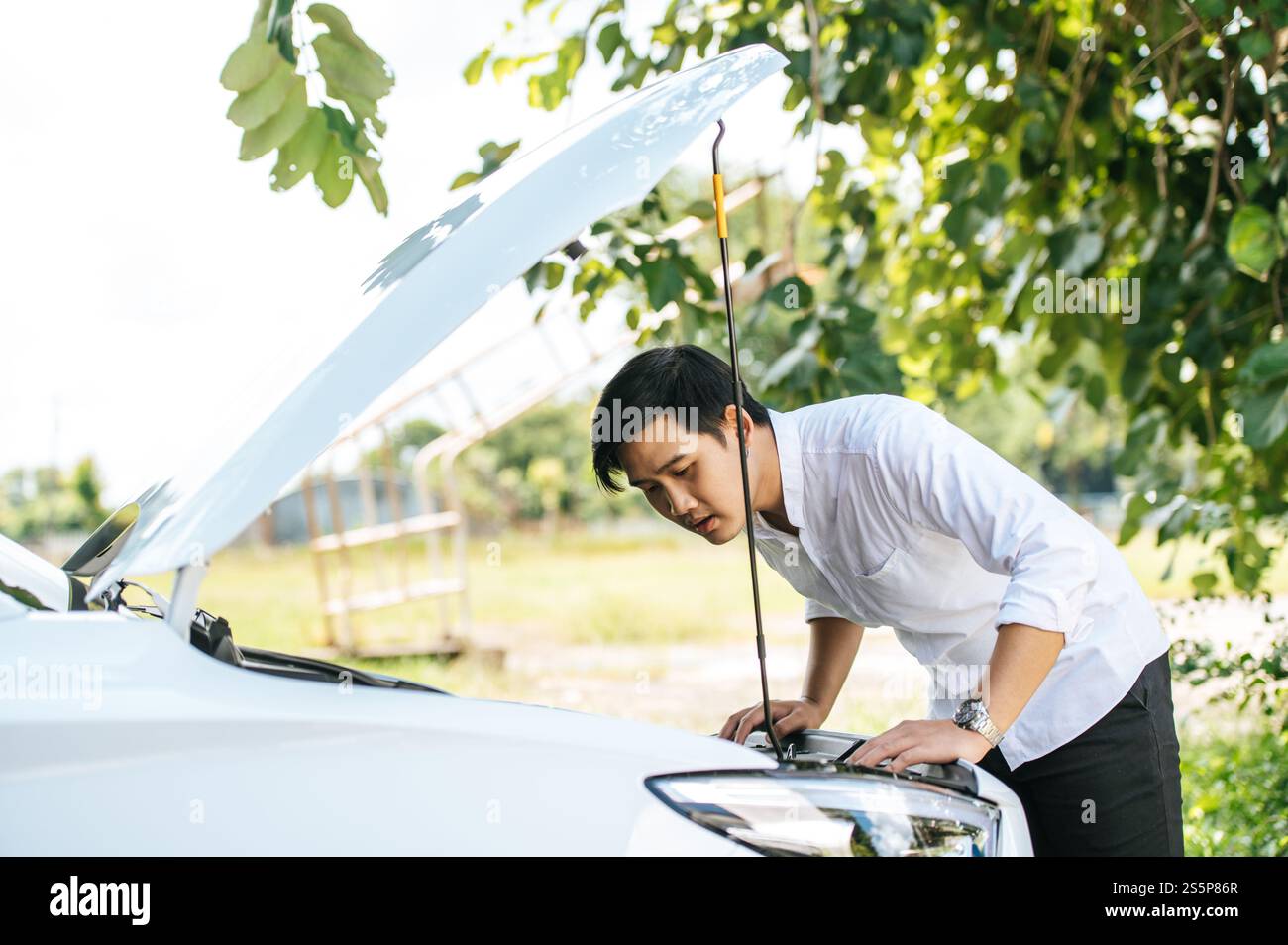 Un uomo apre il cofano di un'auto per riparare l'auto a causa di un guasto. Foto Stock