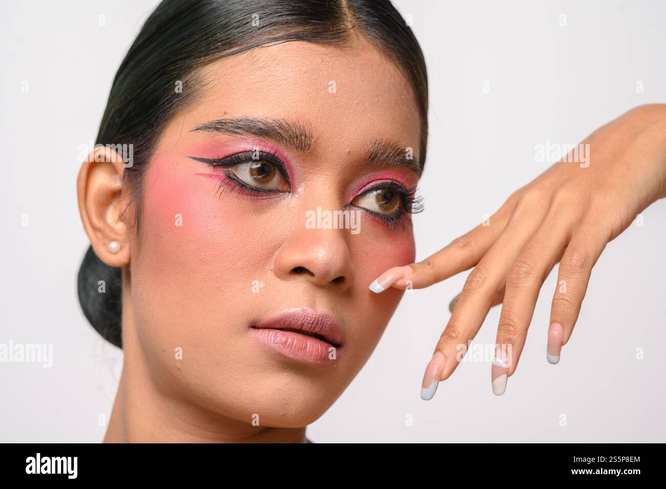 La donna si è messa il trucco rosa e ha messo la mano sul viso. Isolato su sfondo bianco Foto Stock