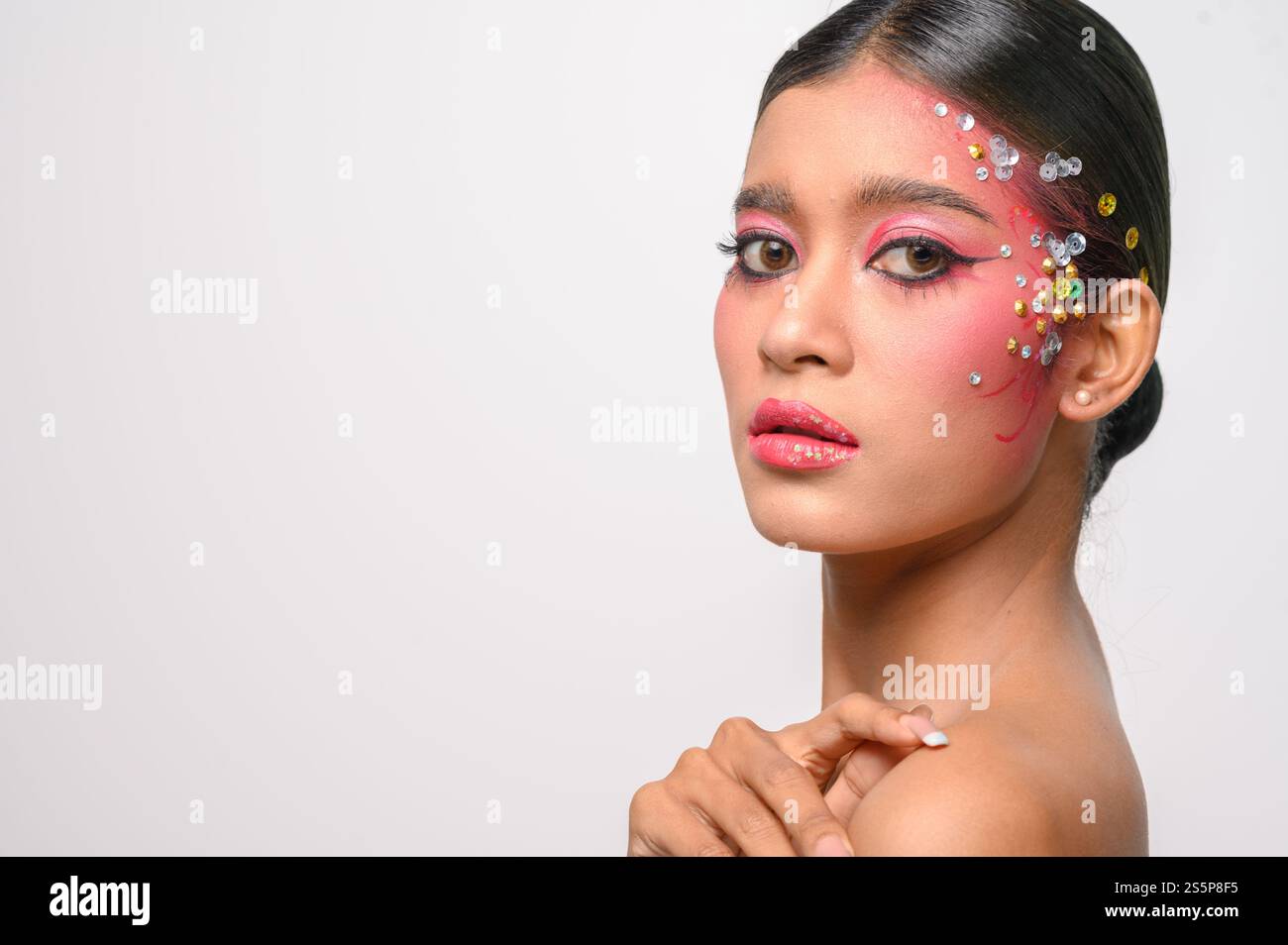 Donna che indossa trucco e decorazioni rosa sul viso. Isolato su sfondo bianco Foto Stock