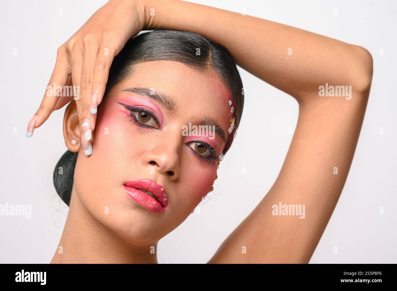 La donna si è messa il trucco rosa e ha messo la mano sul viso. Isolato su sfondo bianco Foto Stock