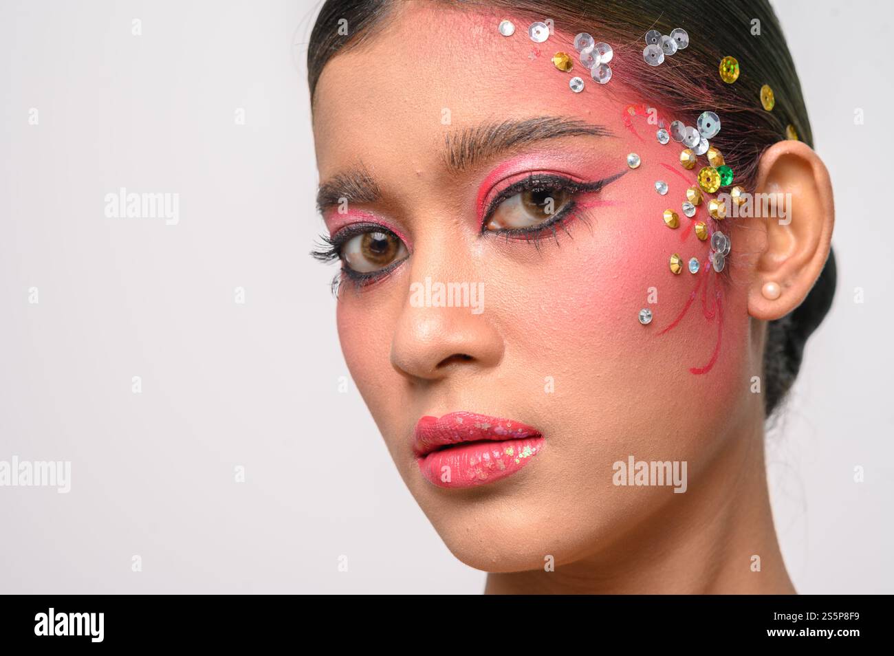 Donna che indossa trucco e decorazioni rosa sul viso. Isolato su sfondo bianco Foto Stock