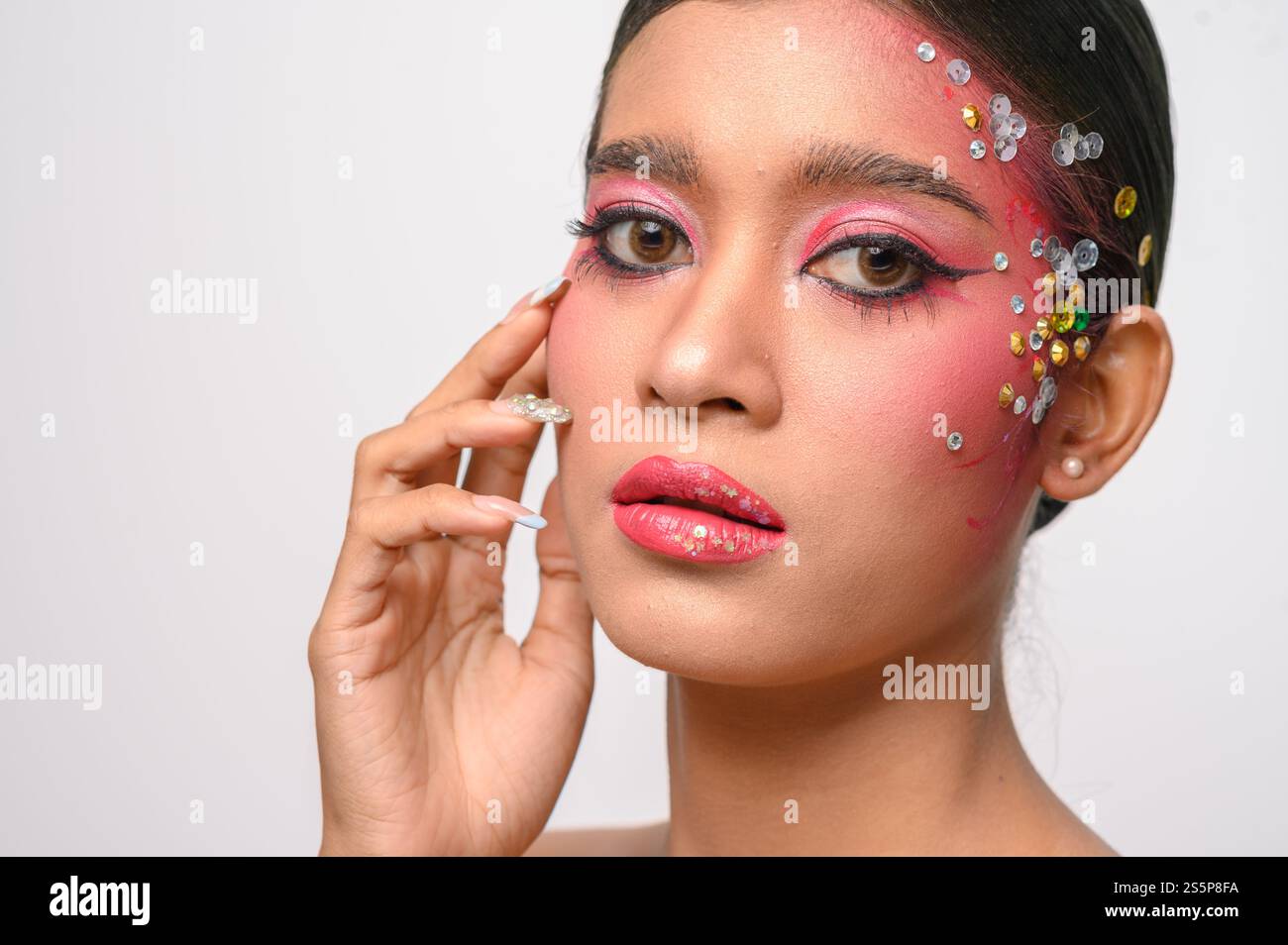 Donna che indossa trucco e decorazioni rosa sul viso. Isolato su sfondo bianco Foto Stock