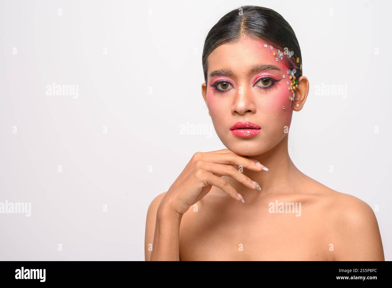 Donna che indossa trucco e decorazioni rosa sul viso. Isolato su sfondo bianco Foto Stock