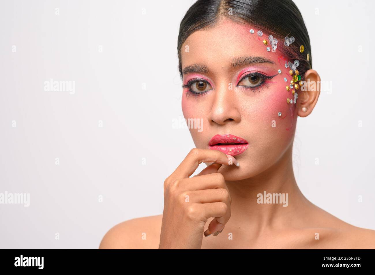 Donna che indossa trucco e decorazioni rosa sul viso. Isolato su sfondo bianco Foto Stock