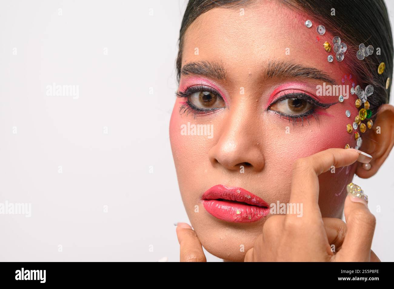 Donna che indossa trucco e decorazioni rosa sul viso. Isolato su sfondo bianco Foto Stock