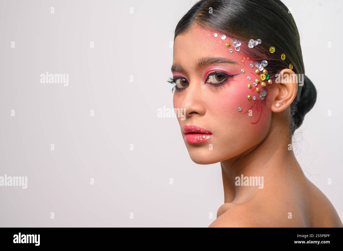 Donna che indossa trucco e decorazioni rosa sul viso. Isolato su sfondo bianco Foto Stock