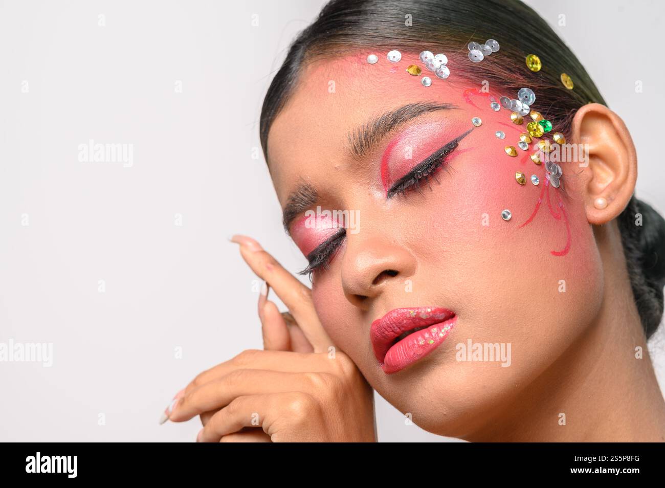 Donna che indossa trucco e decorazioni rosa sul viso. Isolato su sfondo bianco Foto Stock