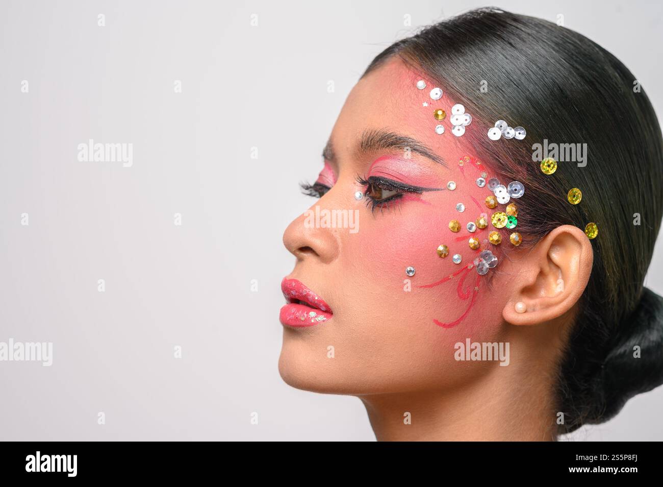 Donna che indossa trucco e decorazioni rosa sul viso. Isolato su sfondo bianco Foto Stock