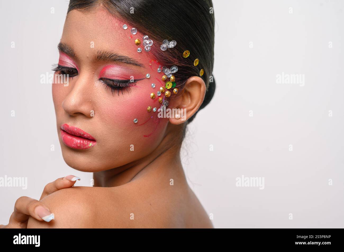 Donna che indossa trucco e decorazioni rosa sul viso. Isolato su sfondo bianco Foto Stock