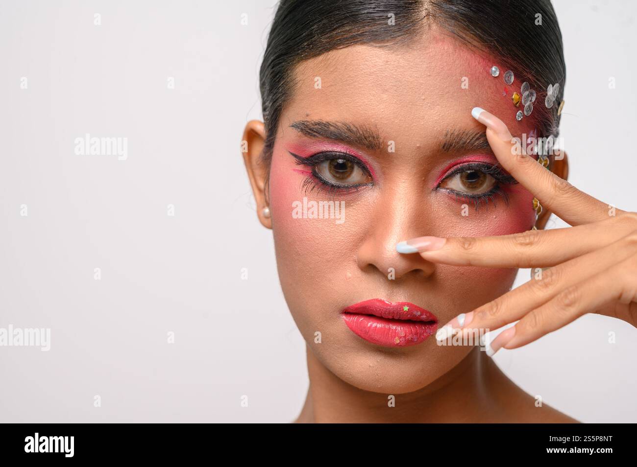 Donna che indossa trucco e decorazioni rosa sul viso. Isolato su sfondo bianco Foto Stock