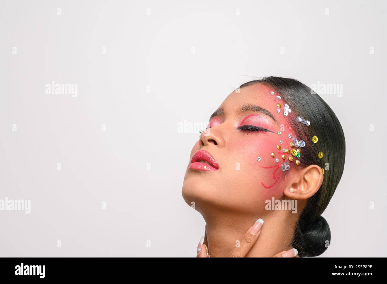 Donna che indossa trucco e decorazioni rosa sul viso. Isolato su sfondo bianco Foto Stock