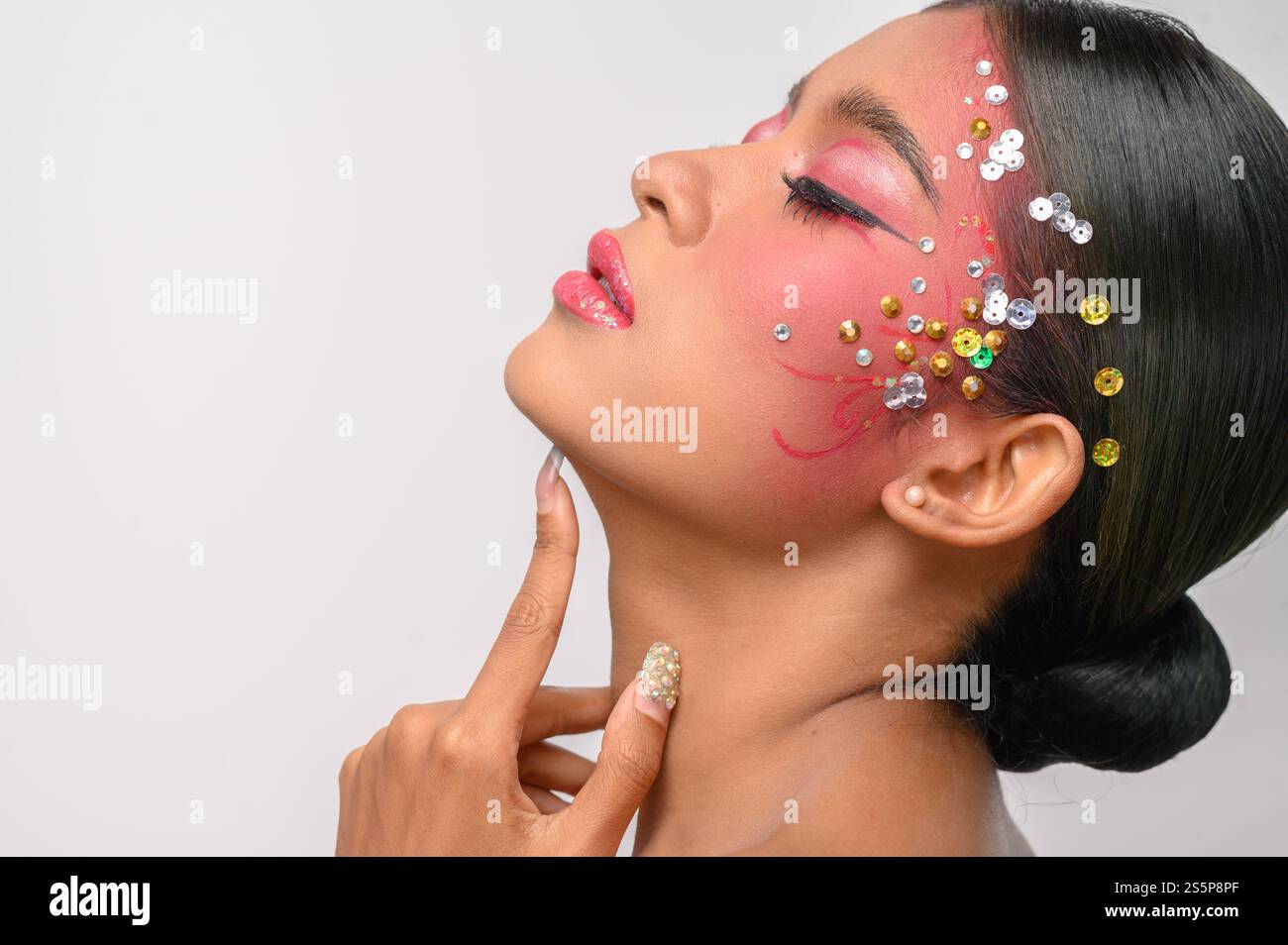Donna che indossa trucco e decorazioni rosa sul viso. Isolato su sfondo bianco Foto Stock
