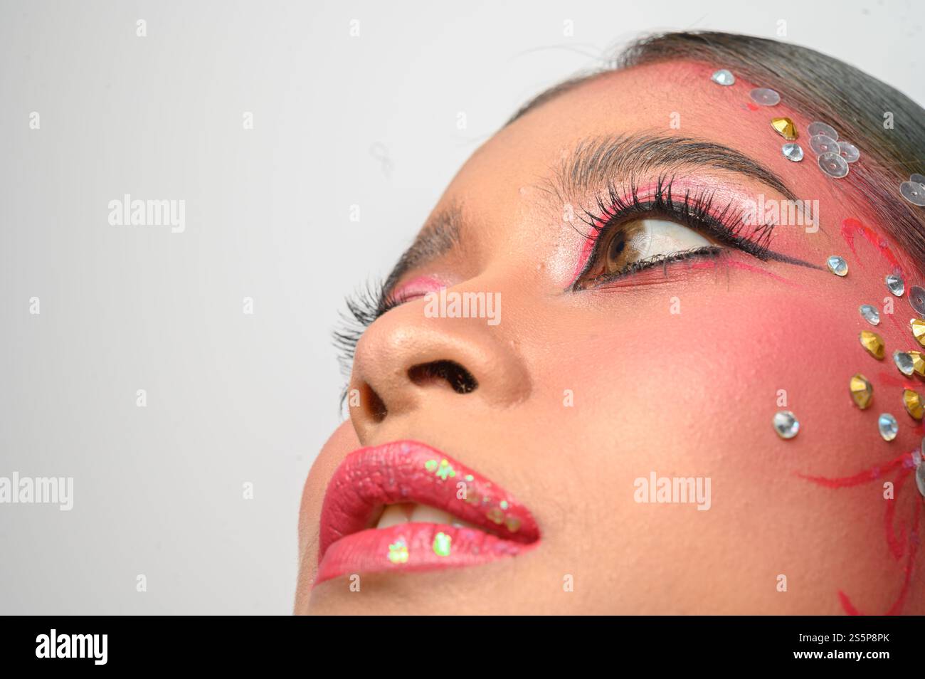 Donna che indossa trucco e decorazioni rosa sul viso. Isolato su sfondo bianco Foto Stock