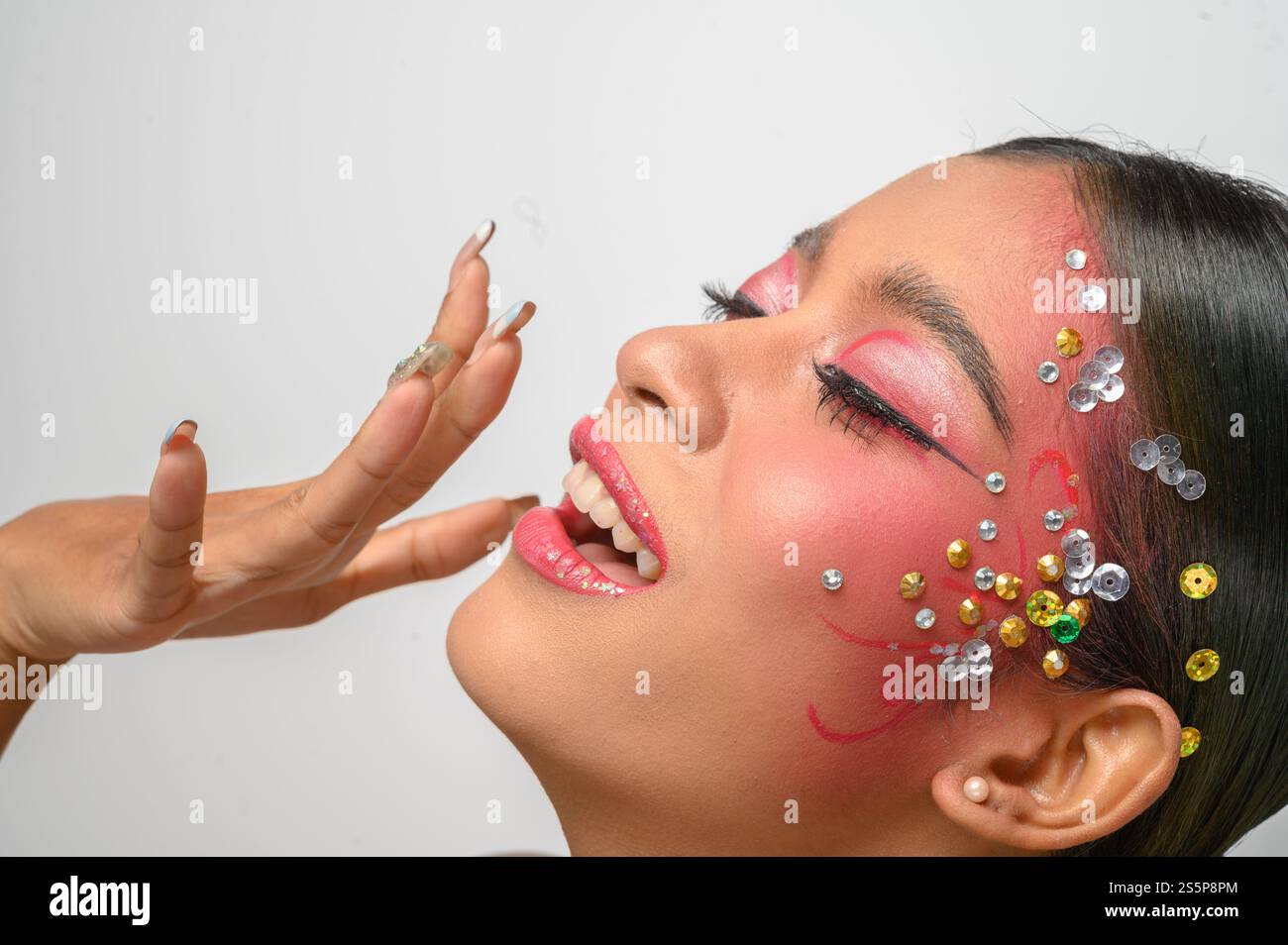 Donna che indossa trucco e decorazioni rosa sul viso. Isolato su sfondo bianco Foto Stock