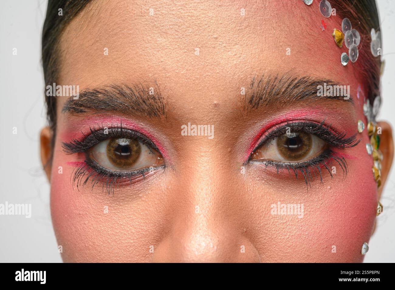 Donna che indossa trucco e decorazioni rosa sul viso. Isolato su sfondo bianco Foto Stock