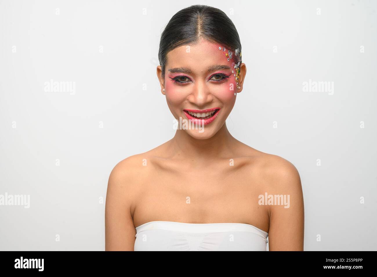 Donna che indossa trucco e decorazioni rosa sul viso. Isolato su sfondo bianco Foto Stock