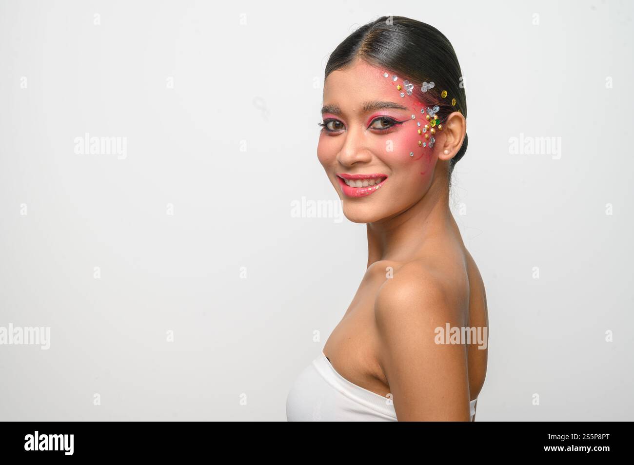 Donna che indossa trucco e decorazioni rosa sul viso. Isolato su sfondo bianco Foto Stock
