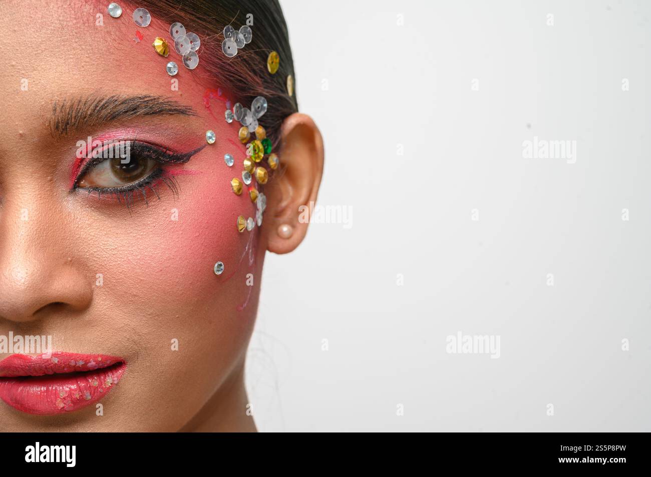 Donna che indossa trucco e decorazioni rosa sul viso. Isolato su sfondo bianco Foto Stock
