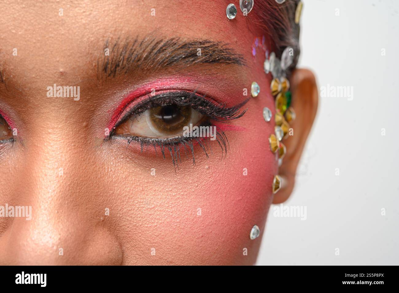 Donna che indossa trucco e decorazioni rosa sul viso. Isolato su sfondo bianco Foto Stock