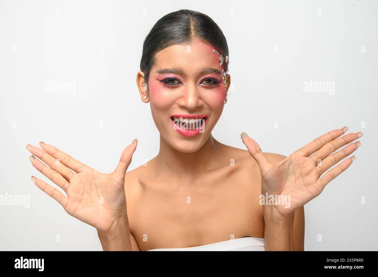 Donna che indossa trucco e decorazioni rosa sul viso. Isolato su sfondo bianco Foto Stock